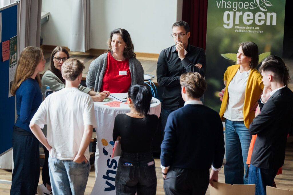 Personen auf einer Tagung bilden eine Kreis und diskutieren Fachthemen.